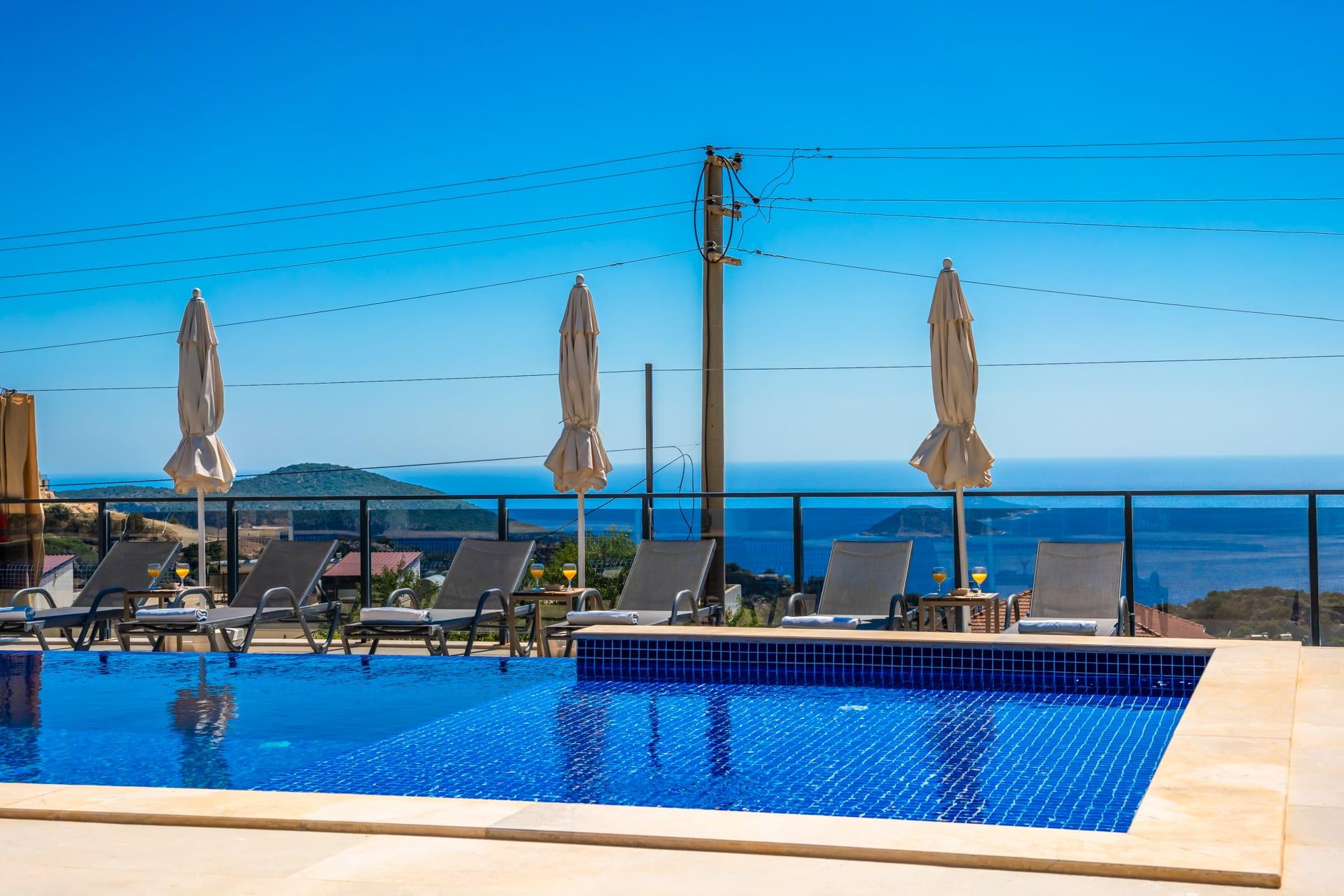 Havuz, şemsiyeler ve arkada deniz